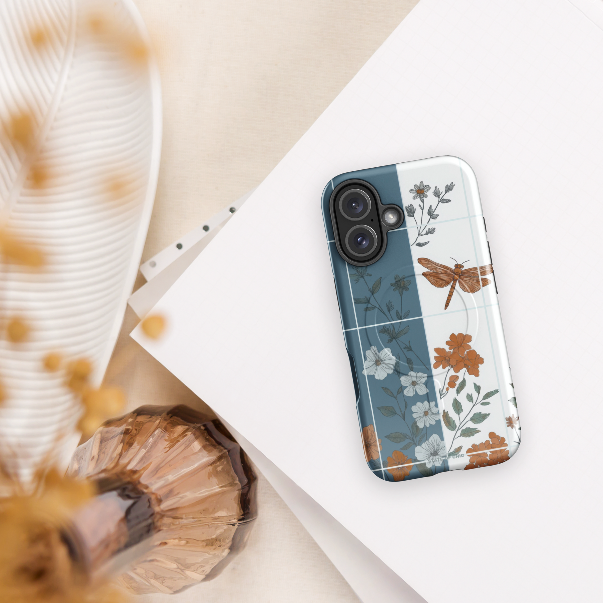 Flat-lay of floral dragonfly iPhone case with white border and symmetrical tile pattern