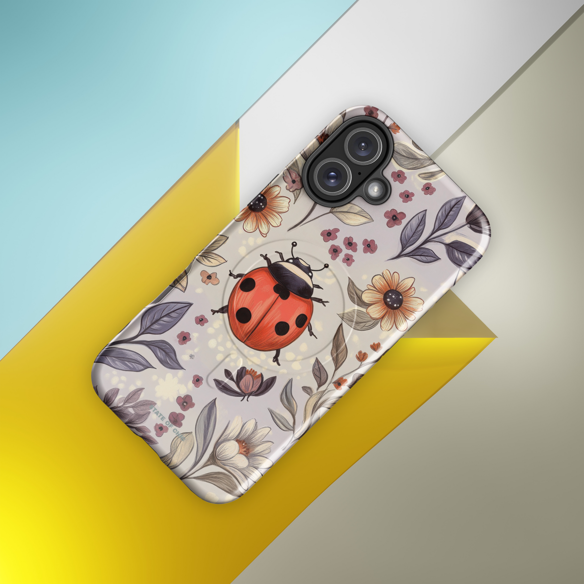 Flatlay of LadyBloom phone case with illustrated chubby ladybug and elegant floral details in a pastel palette.